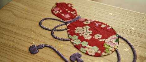 Superficie de madera con un objeto de tela roja con motivos florales y cintas moradas.