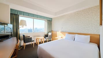 A hotel room with a large bed, a desk with a TV, a chair, a small table, and a window with curtains.