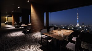 A modern dining area with a cityscape view, featuring a high-rise tower and a city skyline at night. - Tobu Hotel Levant Tokyo (Tokyo)