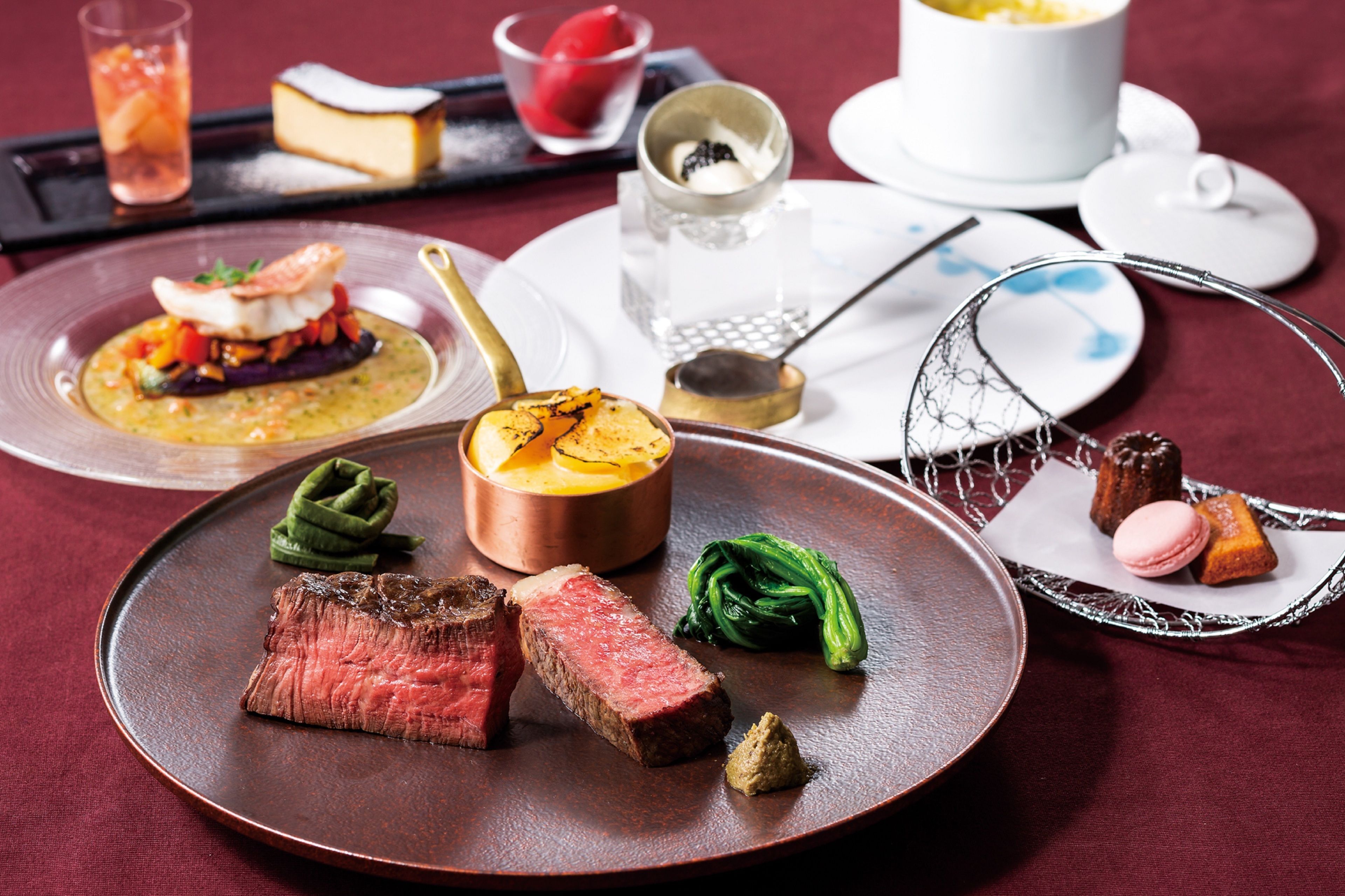 A variety of dishes including steak, vegetables, and desserts on a table.