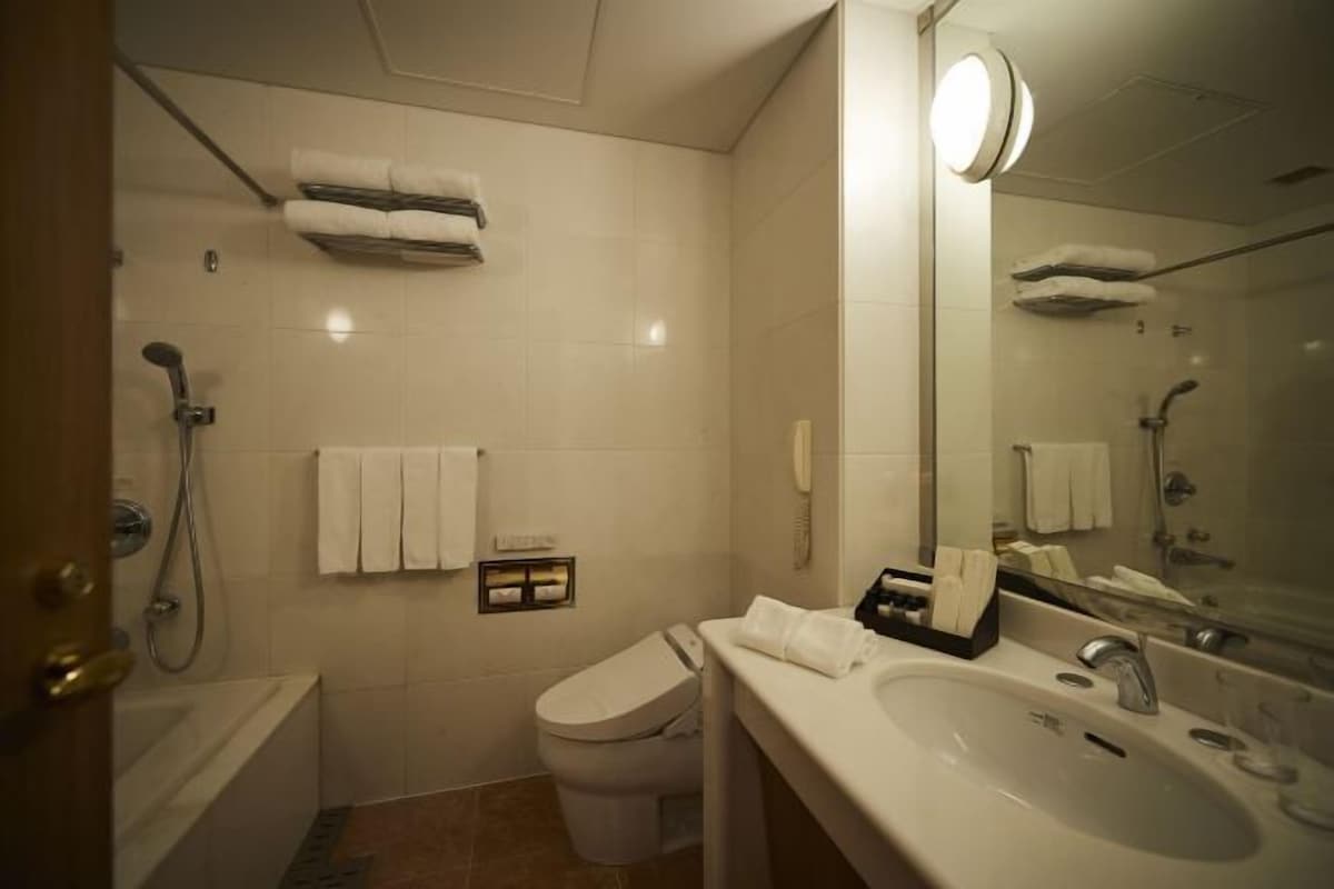 Casa de banho moderna com banheira, sanita e lavatório. Há toalhas e um espelho.