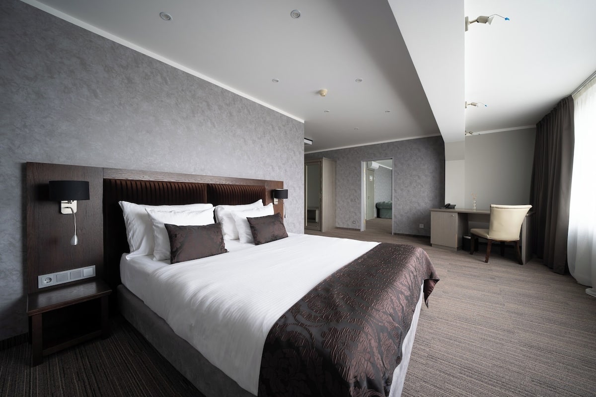 A modern hotel room with a large bed, a desk, and a chair.