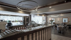 A modern bar area with a long counter, bar stools, and a wine rack. - Bellevue Park Hotel Riga (Riga)