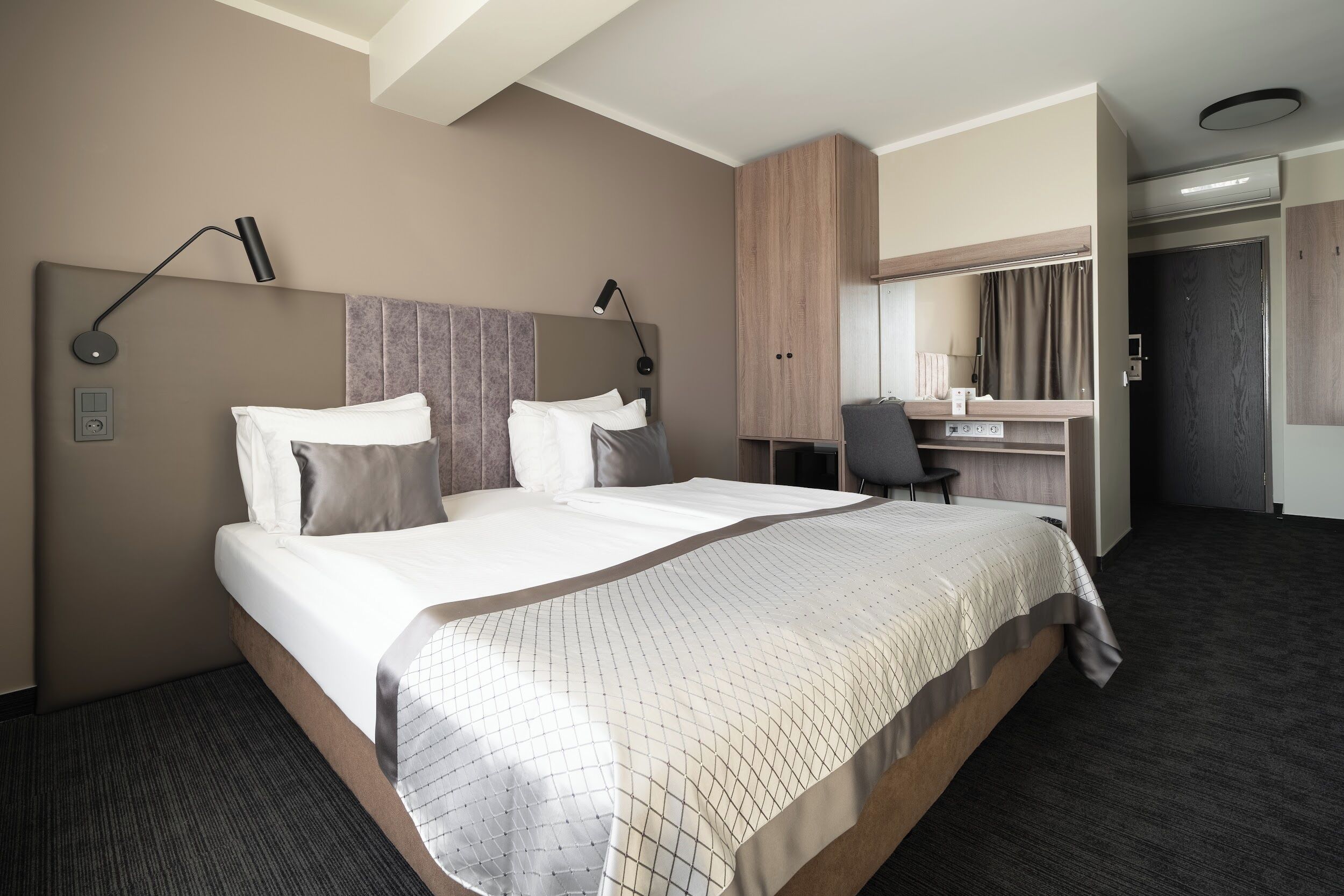 Ein modernes Hotelzimmer mit einem großen Bett, einem Schreibtisch und einem Kleiderschrank.