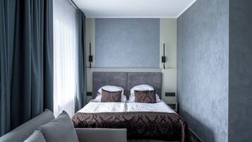 Moderni hotellihuone, jossa on suuri sänky, sohva ja näkymä kaupunkiin.