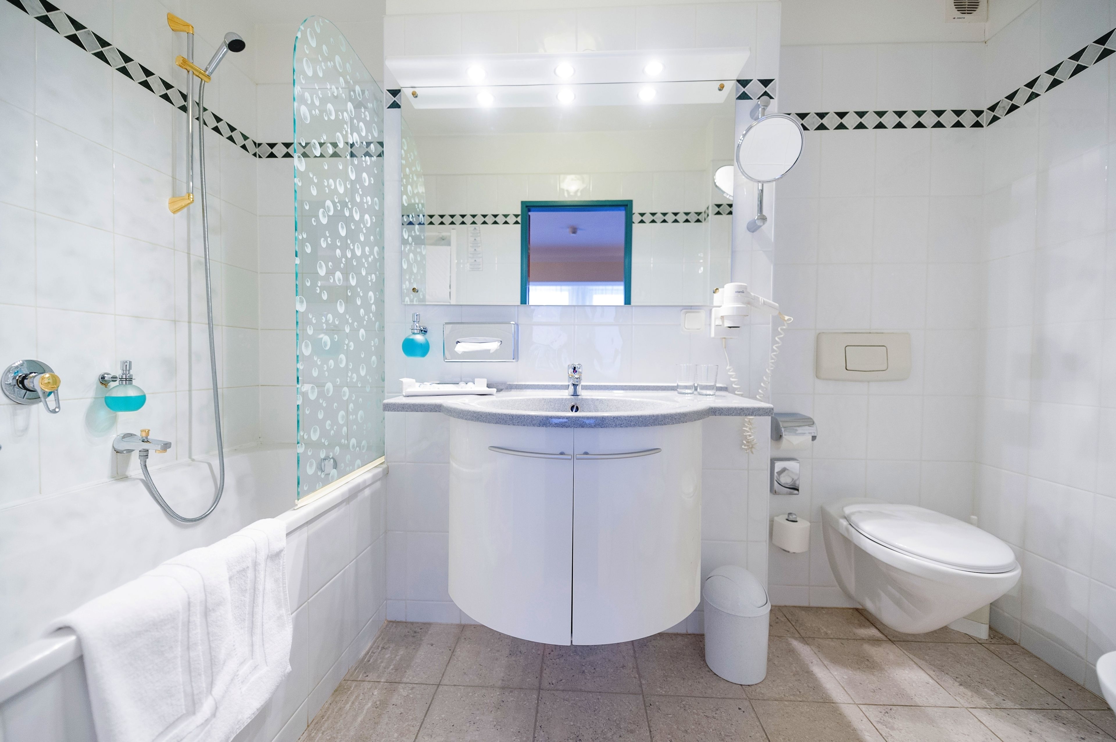 Un baño moderno con cabina de ducha de vidrio, un lavamanos blanco y un inodoro.
