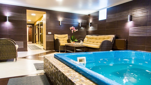 A spa area with a hot tub, wicker furniture, and dark tiled walls. - Bellevue Park Hotel Riga (Riga)