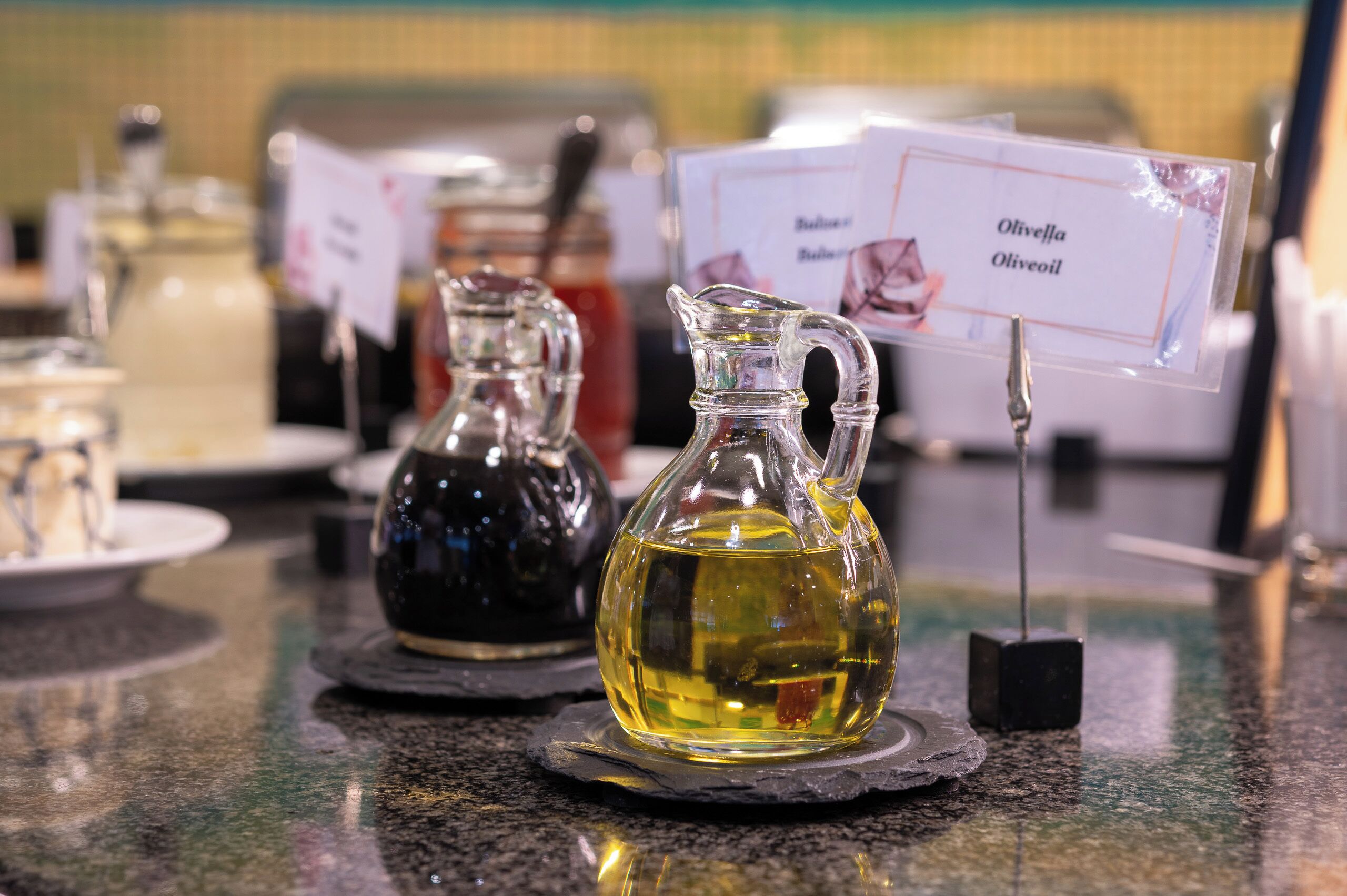 Three glass bottles of olive oil on a counter with labels.