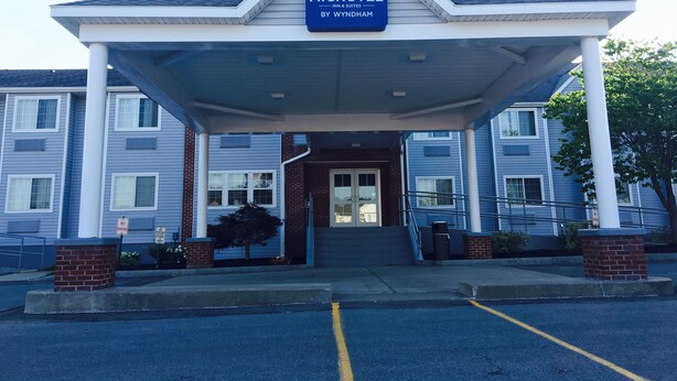 Un bâtiment de la chaîne Microtel Inn & Suites by Wyndham, doté d’une entrée abritée, de piliers en briques et d’un panneau indiquant « Stationnement interdit ».