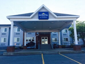 Un bâtiment de la chaîne Microtel Inn & Suites by Wyndham, doté d’une entrée abritée, de piliers en briques et d’un panneau indiquant « Stationnement interdit ».