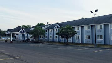 A row of blue motel buildings with a covered entrance and a parking lot in front.