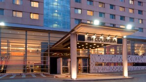 Ein moderner Hotel Eingang mit Glasfassade und überdachtem Bereich, darüber das Schild "TH COLUMBIA".