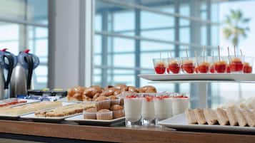 Un buffet con diverse pietanze, tra cui pasticceria, panini e dolci.