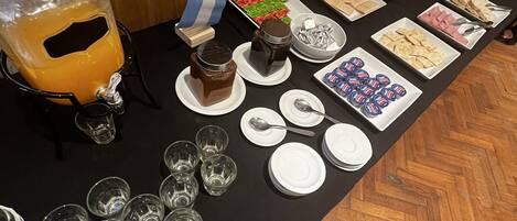 A buffet table with various food items and beverages, including a flag, plates, and glasses.