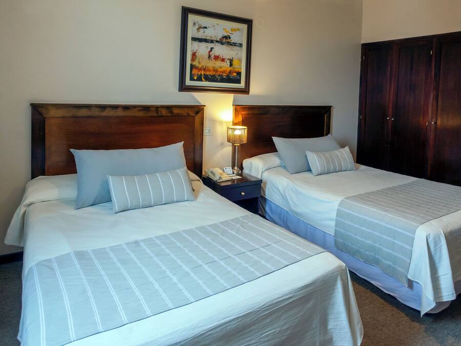 Two single beds with headboards, a nightstand with a lamp, and a wooden wardrobe.