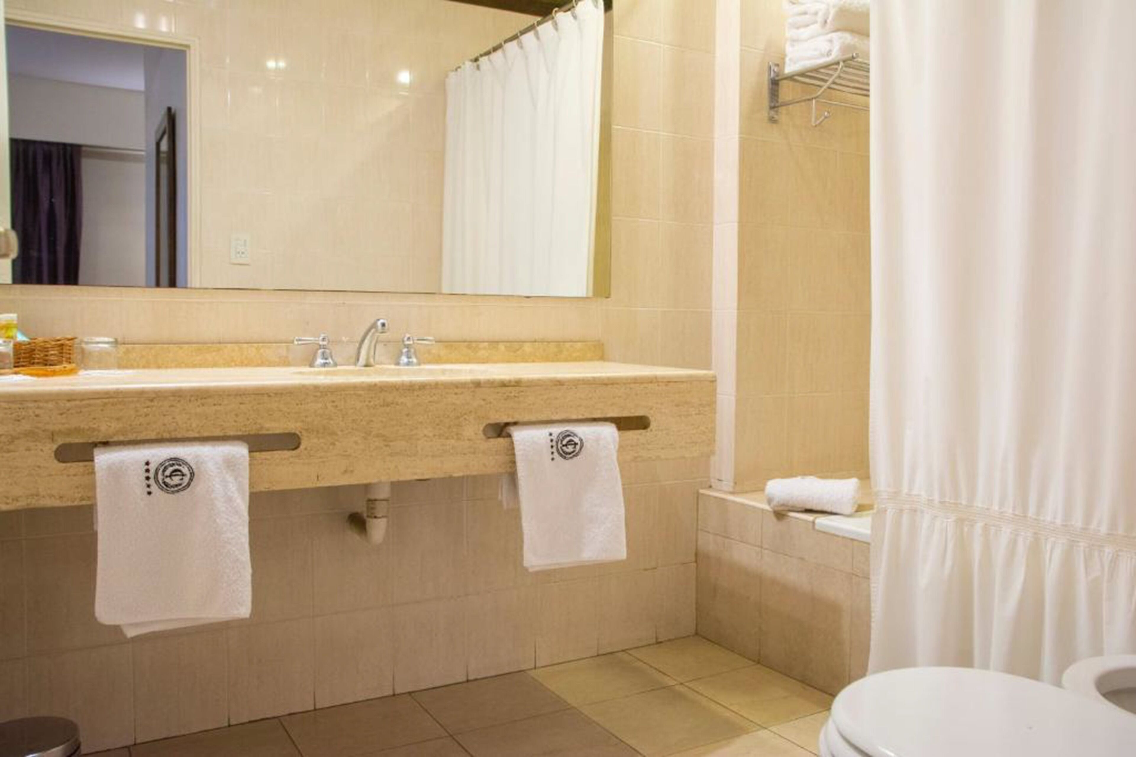 A bathroom with a double sink, a mirror, a toilet, and a shower curtain.