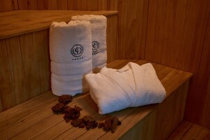 Un banco de madera con dos toallas dobladas y sales de baño esparcidas.