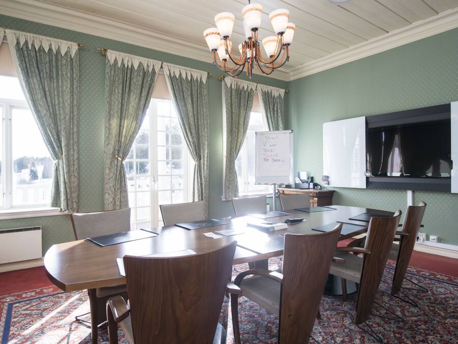 A conference room with a large table, chairs, a whiteboard, and a television.