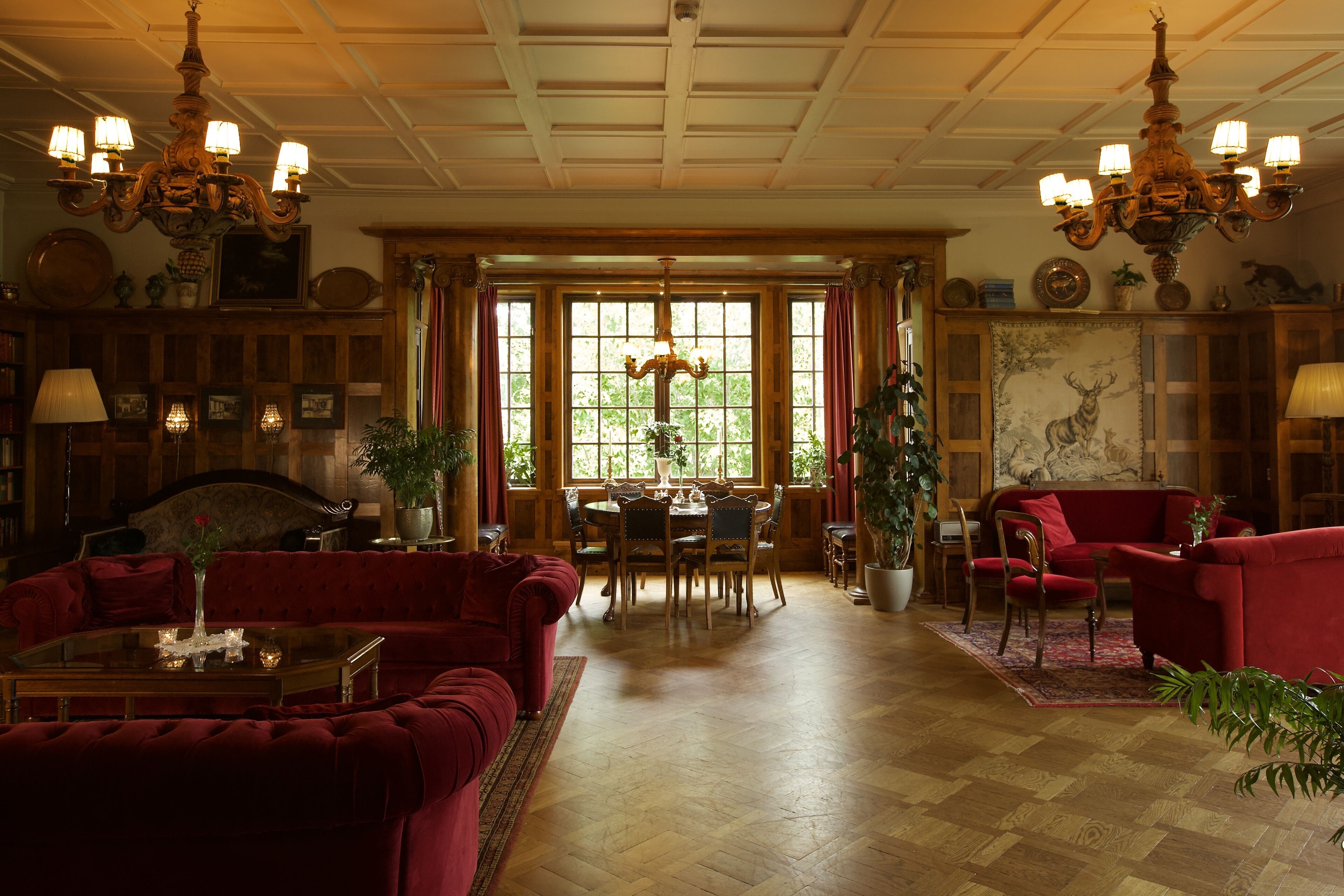 A spacious living room with a red sofa, a dining table, and a chandelier.