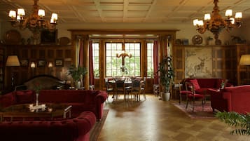 A spacious living room with a red sofa, a dining table, and a chandelier.