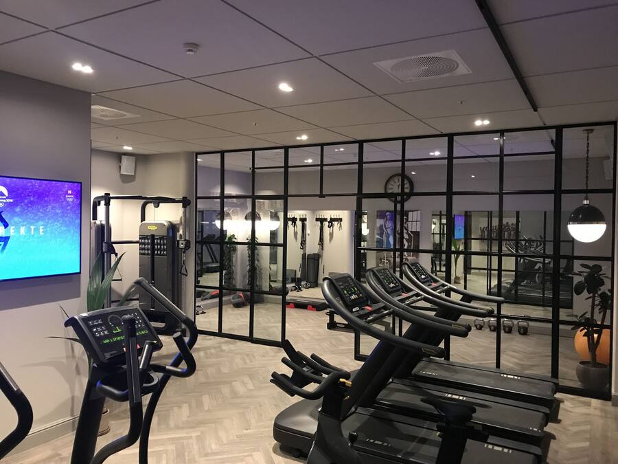 Un gimnasio con cintas de correr, máquinas de pesas y un espejo grande.