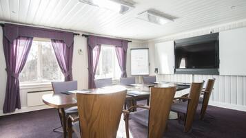 Et mødelokale med en hvidtavle, et fladskærms-tv og et rundt bord med stole.