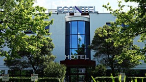 Um hotel chamado ECONTEL com fachada de vidro moderna e uma placa indicando que é um hotel.