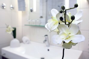 A bathroom with a white sink, mirror, and toiletries. - Amber Econtel München (Munich)