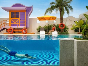A swimming pool with a lifeguard tower, lounge chairs, and palm trees. - Movenpick Hotel Hanoi Centre (Hanoi)