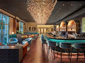 Zona de bar con un cantinero, taburetes y una estantería para vinos.