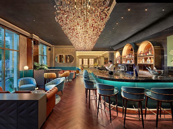Zona de bar con un cantinero, taburetes y una estantería para vinos.