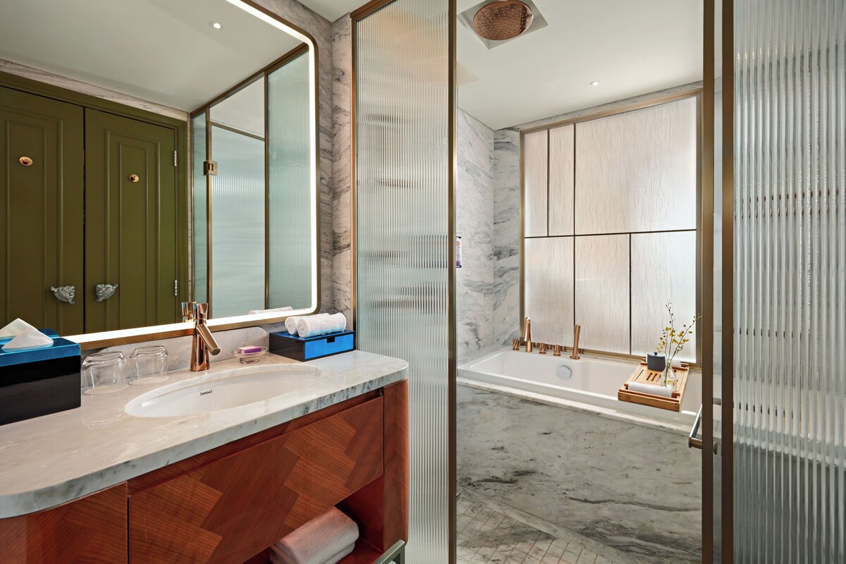 Une salle de bain moderne avec un grand miroir, deux vasques, une baignoire et un meuble-lavabo en bois.