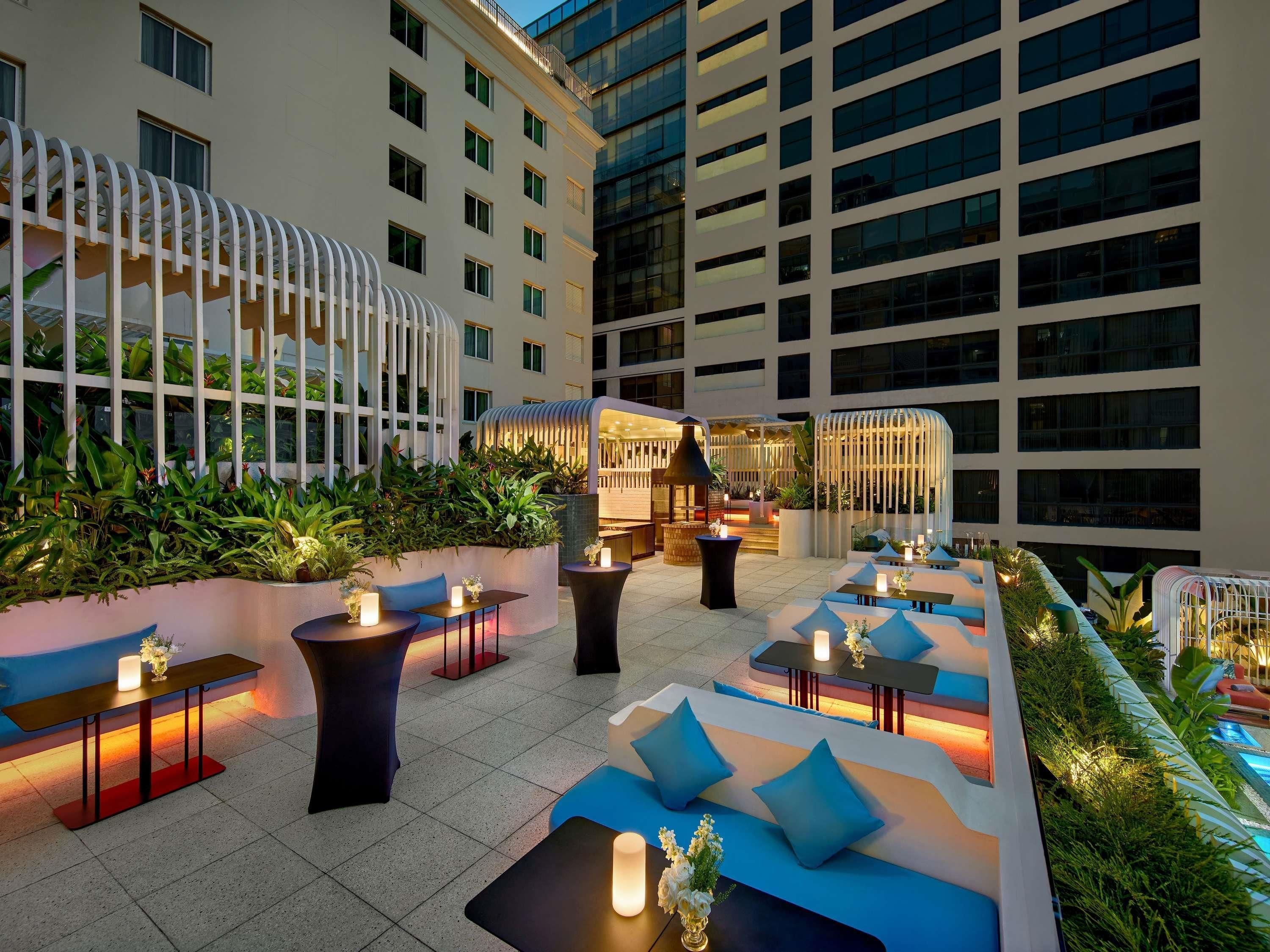 A rooftop terrace with outdoor seating, a pool, and a view of surrounding buildings.