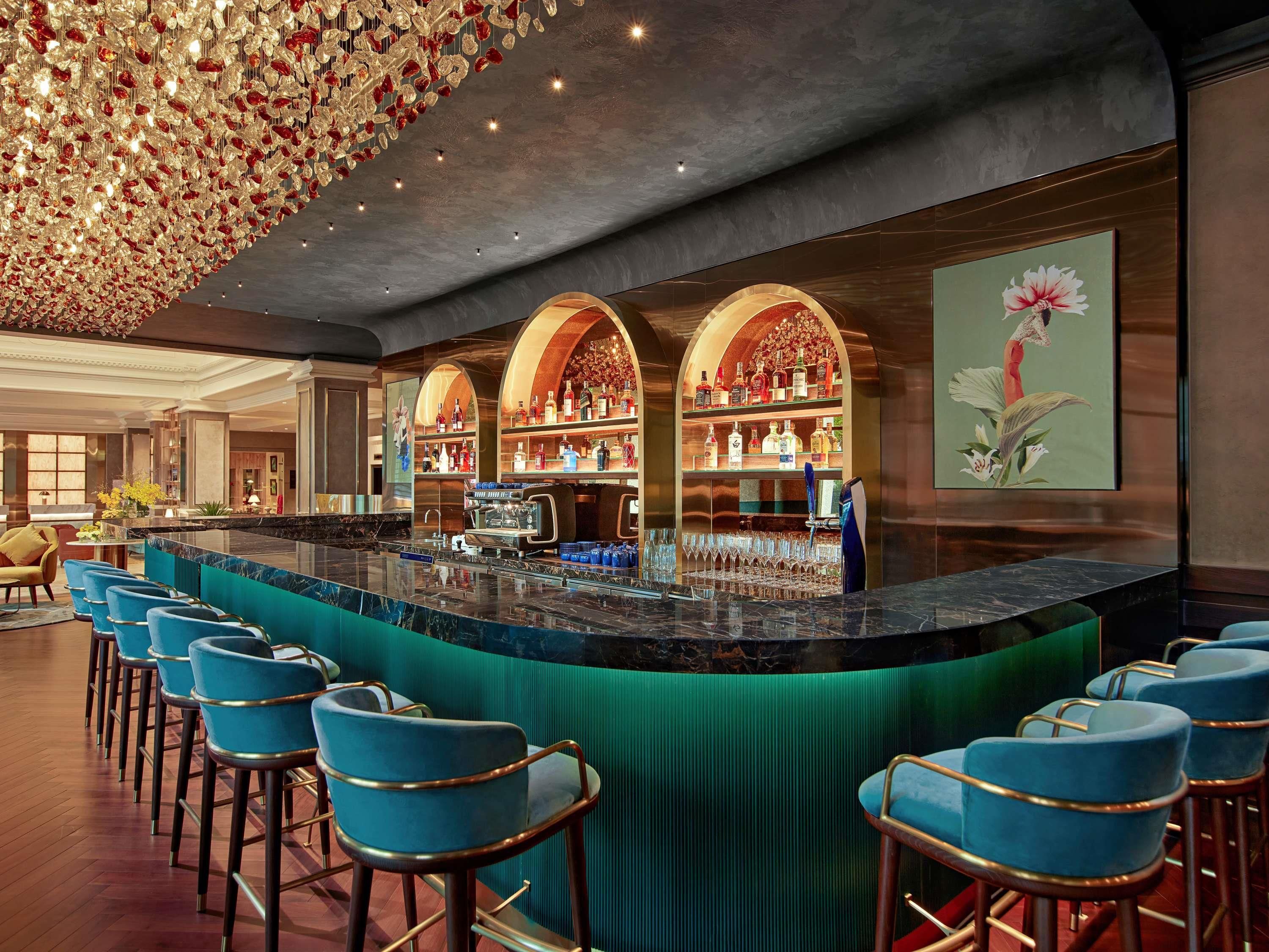 A bar area with a curved counter, blue bar stools, and a decorative ceiling.