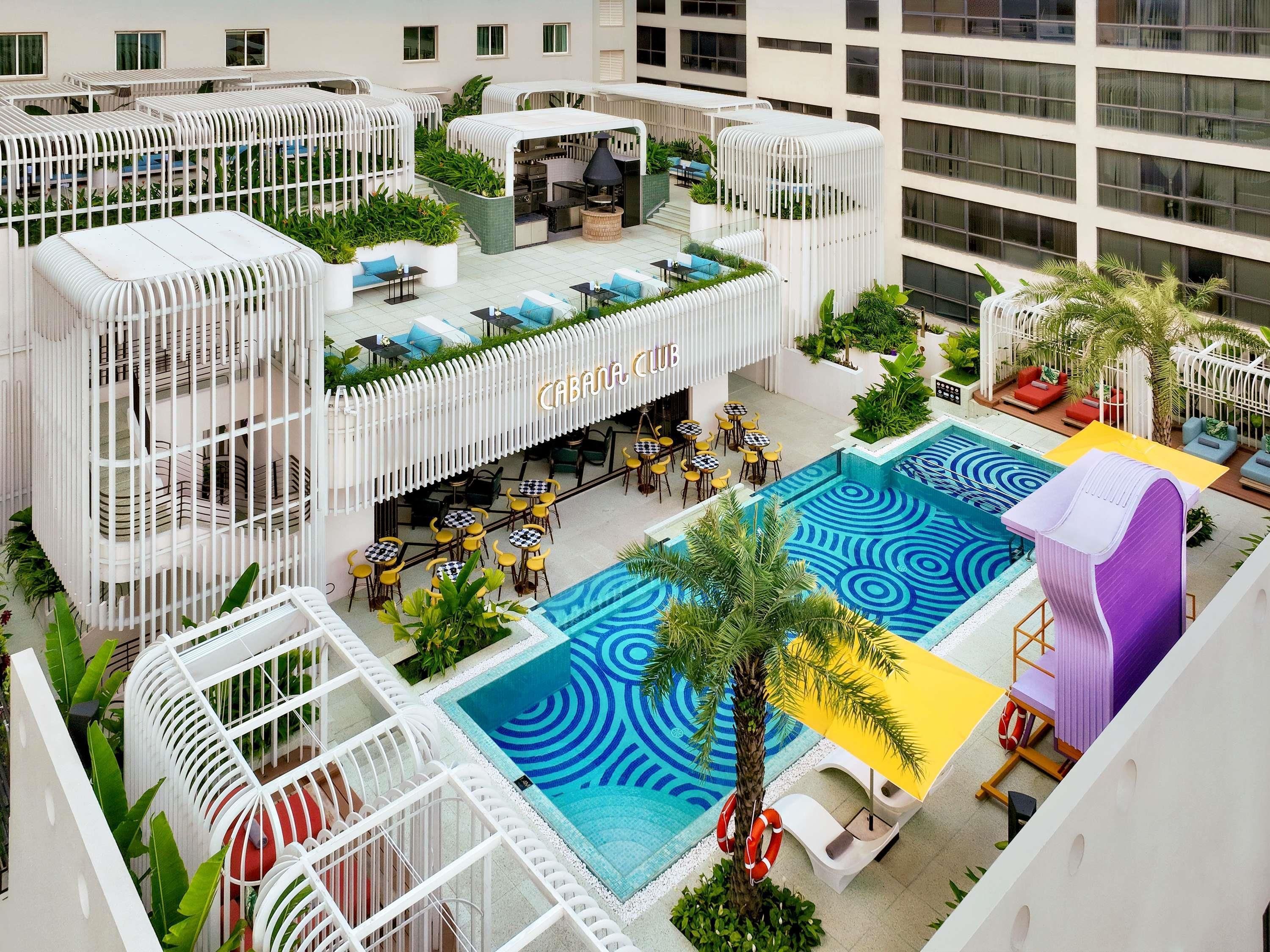 A rooftop pool area with a cabana club, outdoor seating, and a pool with a blue pattern.