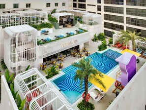 A rooftop pool area with a cabana club, outdoor seating, and a pool with a blue pattern.