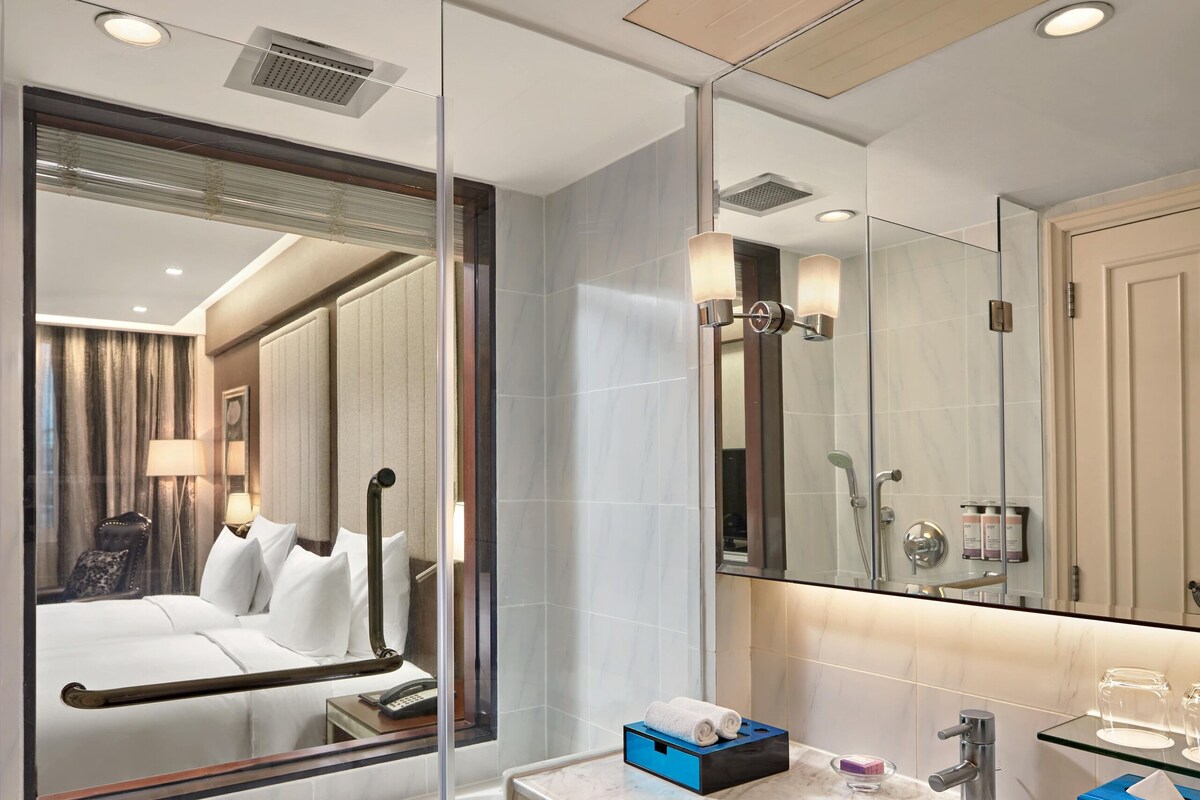 Une salle de bain moderne avec un grand miroir, une baignoire, un meuble-lavabo et une cabine de douche en verre.