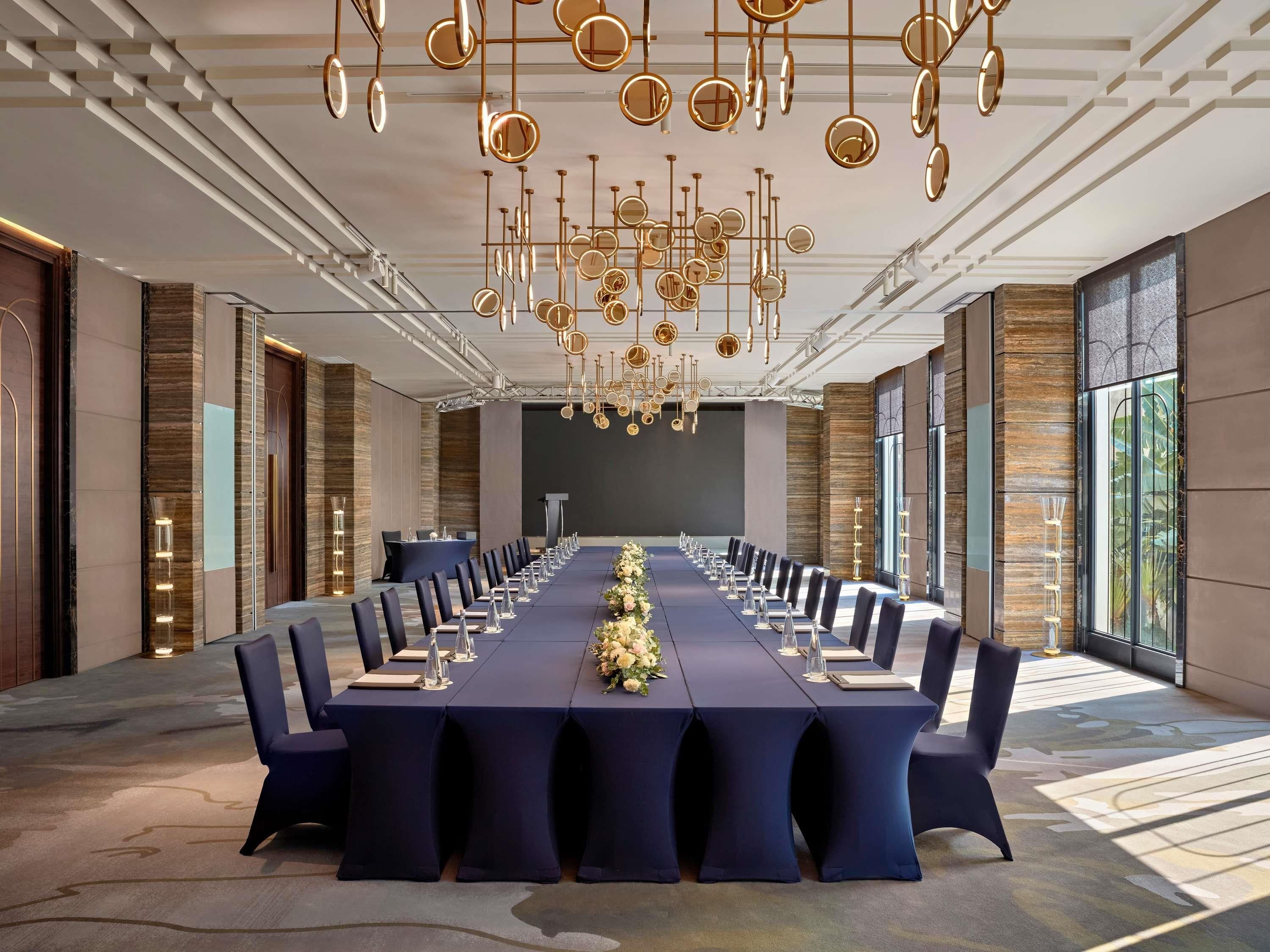 A conference room with a long table, chairs, and a chandelier.