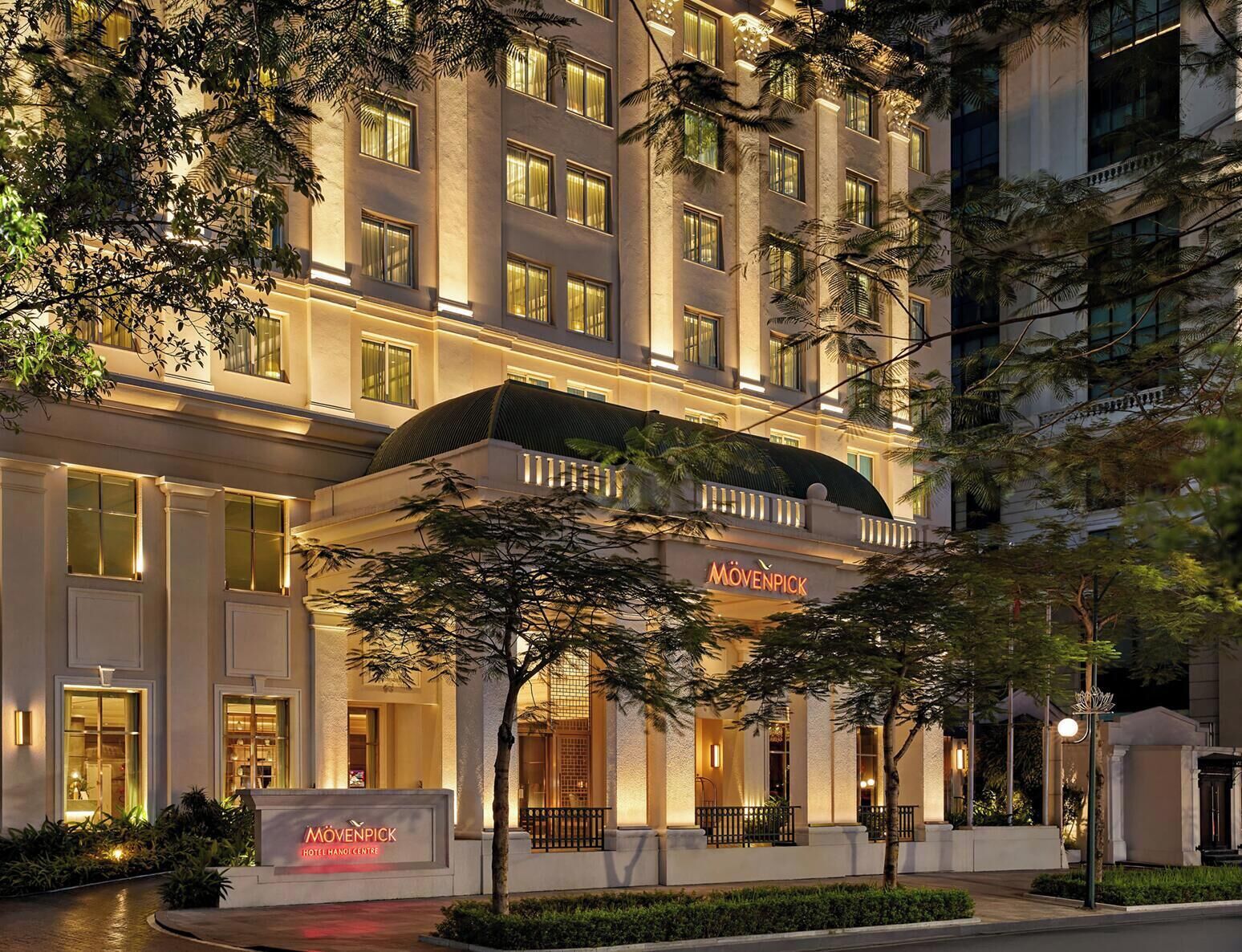 A hotel with a prominent entrance, a signboard, and a well-lit facade.