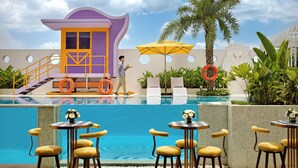 A poolside bar area with multiple tables and chairs, a lifebuoy, and a lifeguard tower.