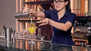 A bartender pouring a drink into a martini glass.