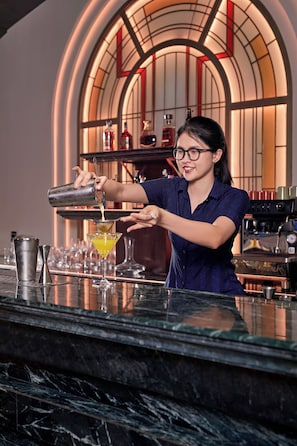 Un barman verse une boisson dans un verre à martini.