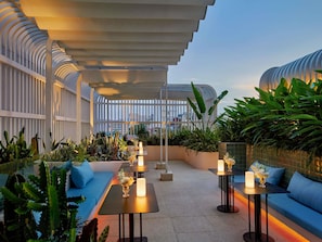 An outdoor seating area with tables, blue sofas, and potted plants. - Movenpick Hotel Hanoi Centre (Hanoi)