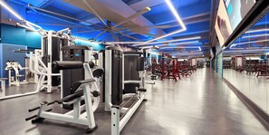 Una palestra moderna con diverse macchine per esercizi, un ampio specchio e un soffitto illuminato di blu.