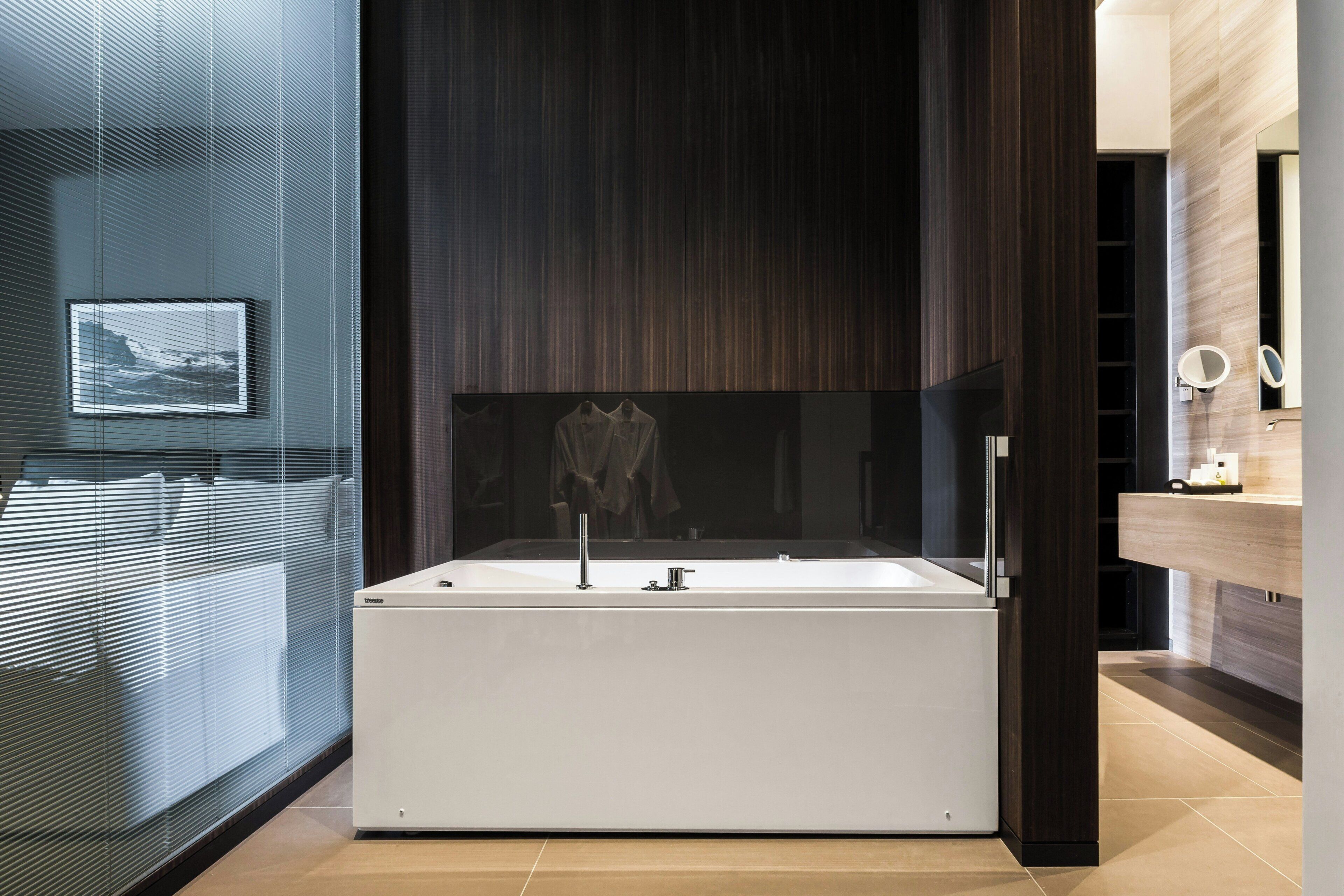 Un bagno moderno con una vasca da bagno indipendente, uno specchio e una televisione a parete.