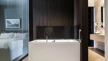 Un bagno moderno con una vasca da bagno indipendente, uno specchio e una televisione a parete.