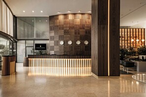 A modern reception area with a wooden panel wall, a reception desk, and a digital screen. - InterContinental Malta by IHG (St. Julian's)