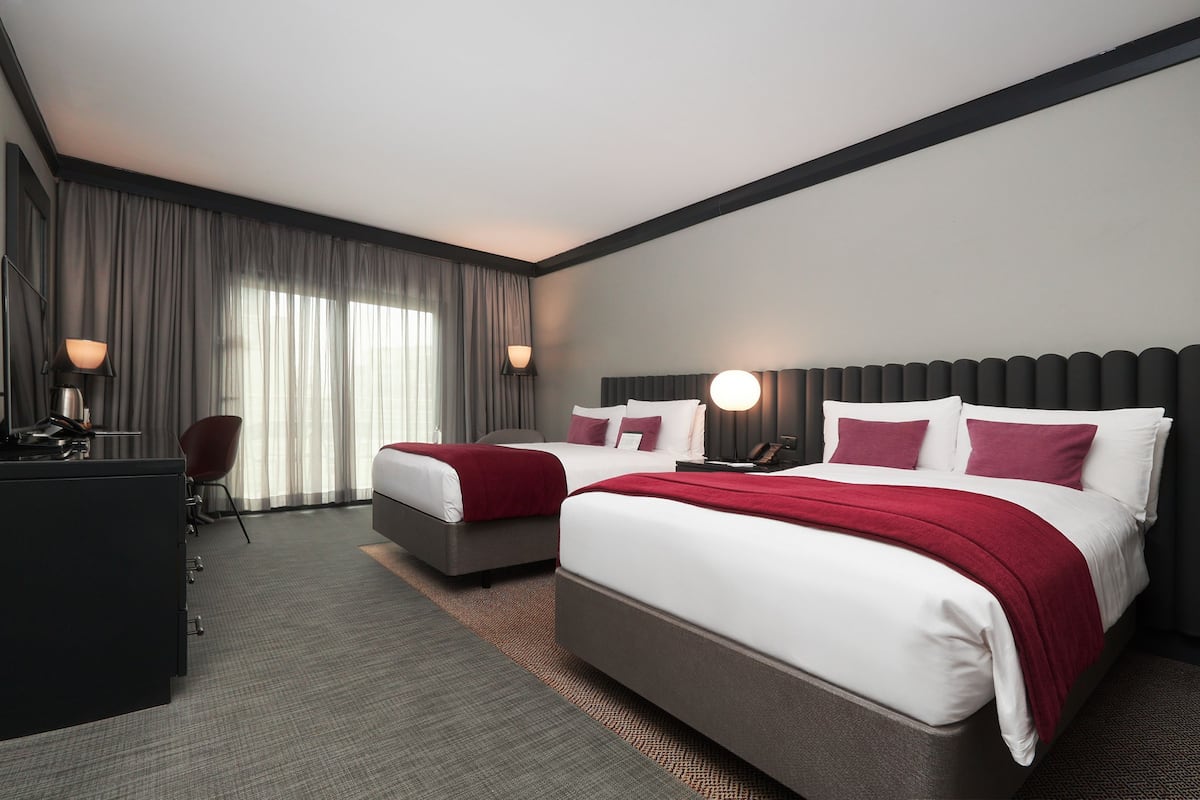 A hotel room with two beds, a desk, and a chair.