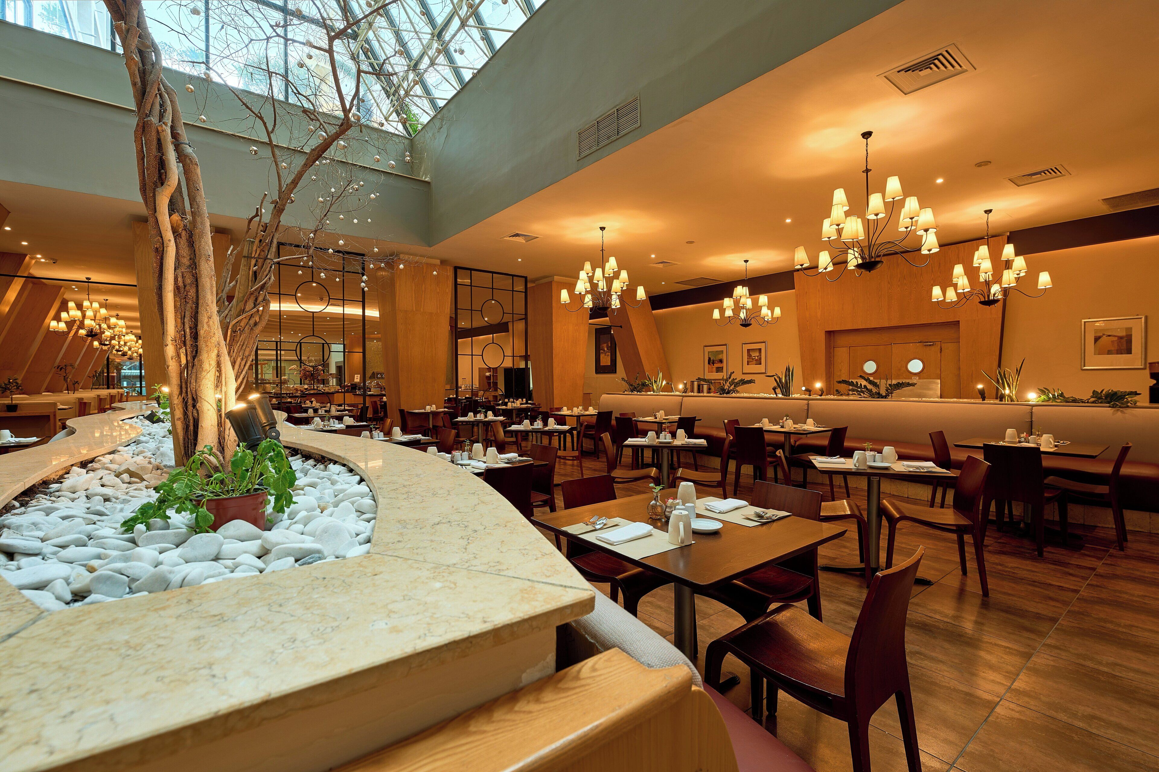 A spacious restaurant with multiple dining areas, a central bar, and a decorative tree in the middle.