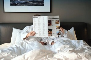 A person lying in bed with a menu or directory in front of them. - InterContinental Malta by IHG (St. Julian's)